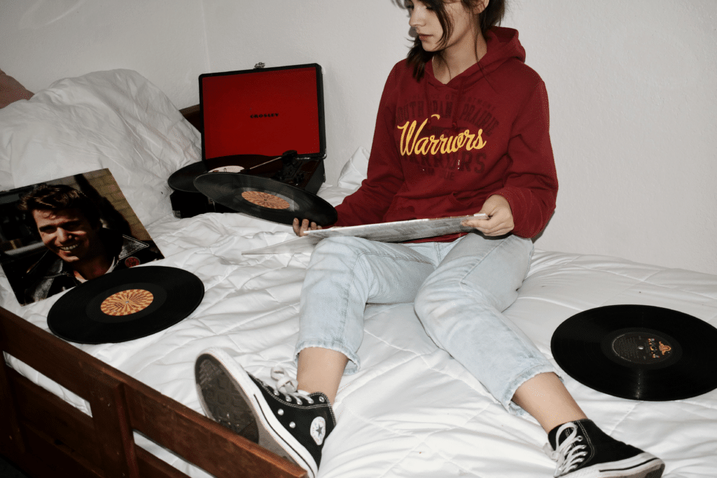 Girl sitting on a bed holding vinyl records
