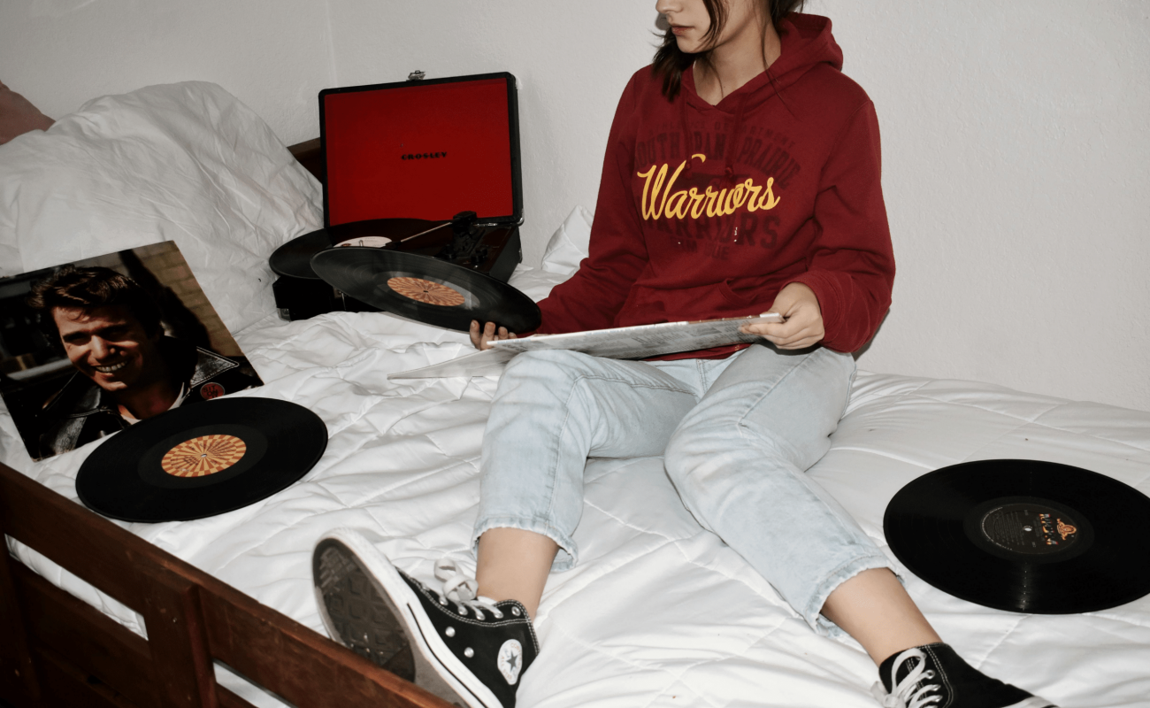 Girl sitting on a bed holding vinyl records